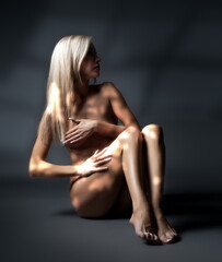 Naklejka premium Art photo, beautiful sexy blonde girl posing nude on a dark background