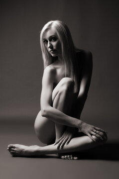 Art photo, beautiful sexy blonde girl posing nude on a dark background