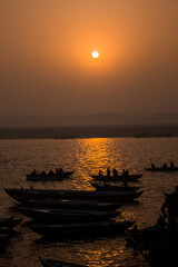 Orange sunset on the river Ganges with small boats