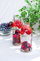 Fototapeta na wymiar Variety of fruit with detox water in glass small bottles. Refreshing summer drinks. Healthy diet concept.