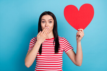 Photo of young girl cover mouth hand oops fail mistake hold big paper heart romantic isolated over blue color background