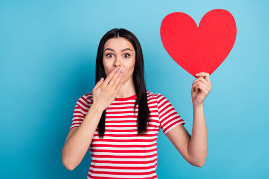 Photo of young girl cover mouth hand oops fail mistake hold big paper heart romantic isolated over blue color background