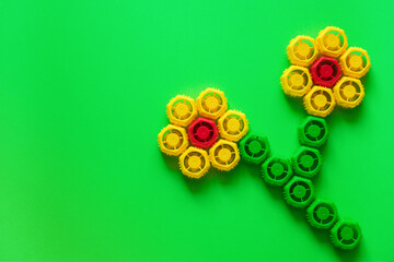 Plastic lids from baby puree in the form of a flower on a green background. Ecology, copy space