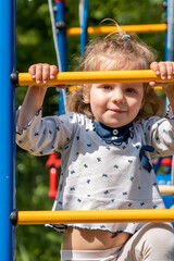 Fototapeta premium Cute toddler girl having fun on playground. Happy healthy little child climbing on different equipment.