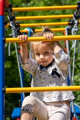 Obraz premium Cute toddler girl having fun on playground. Happy healthy little child climbing on different equipment.