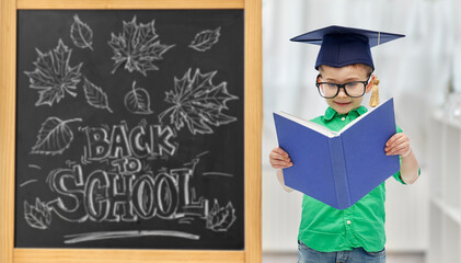 education, learning and people concept - happy little student boy in bachelor hat or mortarboard...
