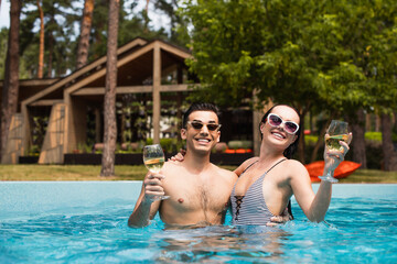 Smiling vacationers relaxing with wine in swimming pool