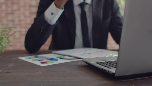 Paper Glass Of Coffee Is Taken And Drinks By A Black Man Businessman From An Office Desk Working Behind A Laptop, Close-up.