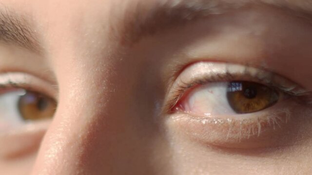 Young woman brown eyes with mascara blinking. Lookout from and in the camera. Studio still shot with dramatic light close-up high quality video.