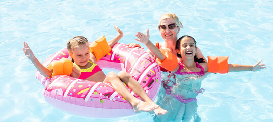 Happy family in the pool, having fun in the water, mother with kids enjoying aqua park, beach...