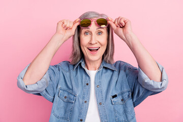 Photo of astonished aged lady hand eyewear wear blue shirt isolated on pastel pink color background