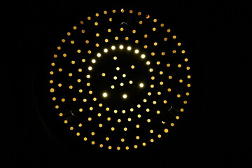 Black background with circular geometric pattern with yellow and orange colors.  Decorative wallpaper.