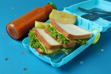 Lunch box with tasty food on blue background