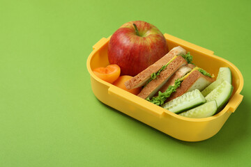 Lunch box with tasty food on green background