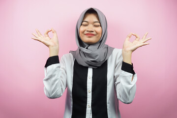 Beautiful young muslim woman with hands meditating sign, smiling comfortable and happy, isolated on pink background