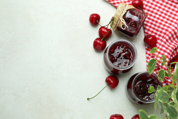 Cherry jam and ingredients on white textured table