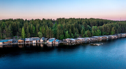 Obraz premium Evening panorama on Karelian lake Kovdozero. Wooden boat garages of fishermen. Settlement Zelenoborsky, Kandalaksha, Murmansk region, Kola Peninsula. Polar day. Karelian landscape