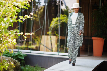 Obraz premium Beautiful african american woman natural makeup wear fashion clothes casual black and white dress code office style total blouse and pants suit and hat.