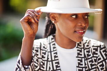 Obraz premium Beautiful african american woman natural makeup wear fashion clothes casual black and white dress code office style total blouse and pants suit and hat.