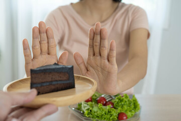 Diet concept. Women refuse chocolate cake and eat salad for good health.
