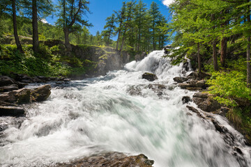 Famous Fontcouverte Waterfall in the Claree Valley surrounded by larch trees in summer. Vallée de la Claree in Hautes Alpes (Cerces Massif), Southern French Alps, France