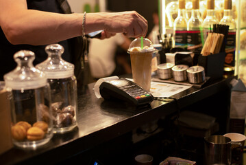 Obraz na płótnie Canvas ice coffee in a glass and a payment terminal. Small business mini coffee shop drink takeaway.