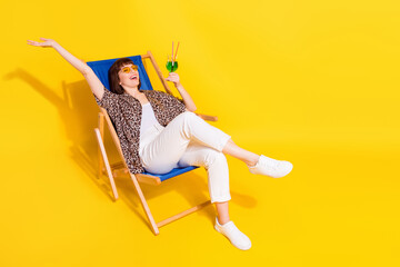 Full body photo of impressed lady sit drink beverage wear eyewear shirt trousers isolated on yellow color background