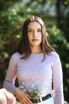 Tender teen girl with flowers in jeans looking at camera