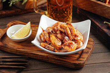 Roasted garlic shrimp appetizer with beer on wooden background