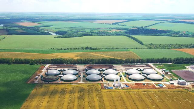 Flight over biogas power plants. Aerial view of big biogas plant between green agricultural fields