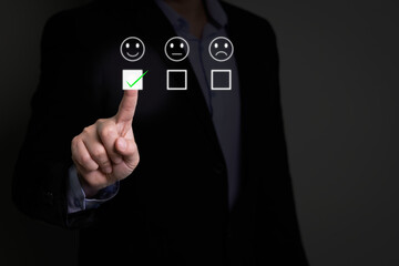 Businessman hand using a virtual touchscreen to select a happy face icon and green checkmark. Concept of excellent customer satisfaction, positive service feedback, and voting for the best experience