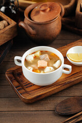 Bowl of ukha fish soup with lemon on the wooden background
