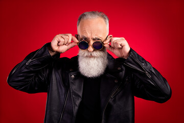 Photo of aged handsome man serious confident hand touch sunglass hipster cool isolated over red color background