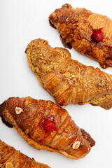 Beautiful handmade delicious croissants decorated with berries and nuts on a white background