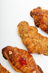 Side view of fresh delicious croissants decorated with berries and nuts on a white background