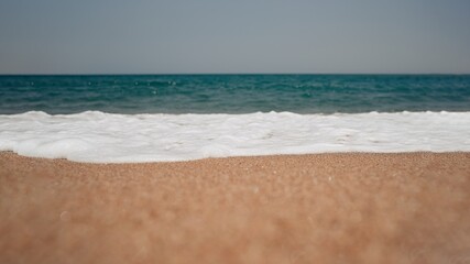 Fototapeta na wymiar Soft wave of blue ocean on sandy beach. Background. Selective focus 