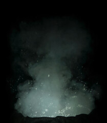 Fototapeta na wymiar fast shutter photo of small water explosion with smoke and splashing water drops isolated on black background. witch's cauldron concept photo.