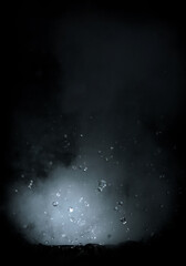 fast shutter photo of small water explosion with smoke and splashing water drops isolated on black...