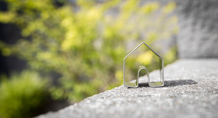 Close-up of a small metal house in front of a blurred nature background