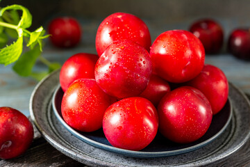 Chinese or Korean red plum in a plate on the table closeup. Summer or autumn harvest	