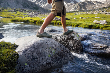 Hiker man crossing river in the mountains