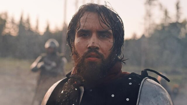 Handsome Medieval Knight King on Battlefield, Looking at Camera. Portrait of Mighty Warrior Soldier Contemplating Victory. War, Invasion, Conquest. Dramatic Scene in Cinematic Historic Reenactment