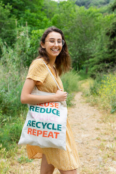 Delighted woman with eco friendly shopping bag in park