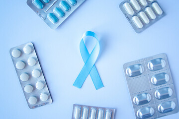 Blue ribbon symbol of prostate cancer with many pills and drugs clusters on bright background. Cancer awareness, cure, treatment concept. Oncology and carcinoma, ribbon