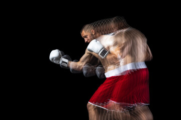 Young professional boxer in red shorts training, exercising over black background. Stroboscope...
