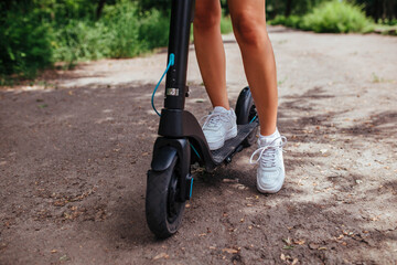 Cute brunette girl rides on an electric scooter in the park she is wearing a white shirt. concept...