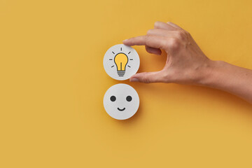A paper circle with a smile and a light bulb above it. The joy of creating a creative idea and...