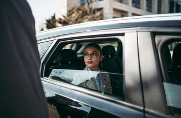 Good looking young business woman sitting on backseat in luxury car. She using her smart phone, smiling and looking outside. Transportation in corporate business concept. - obrazy, fototapety, plakaty