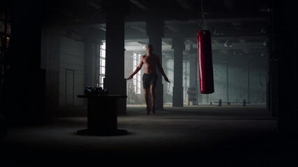 Male boxer jumping on skipping rope. Man with naked torso using jump rope - obrazy, fototapety, plakaty