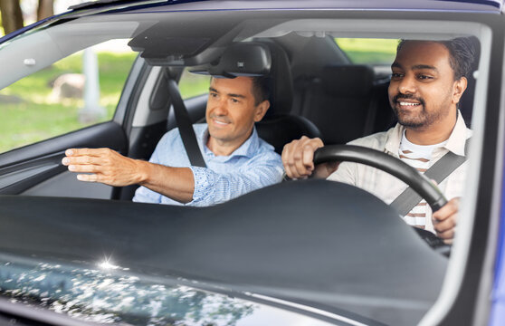 driver courses and people concept - car driving school instructor teaching young man to drive